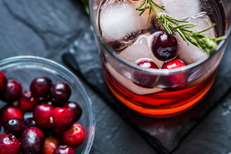 Cranberry juice cocktail with bowl of cranberries on slate